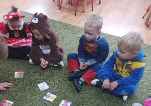 Dzieci siedzą w przebraniach na dywanie